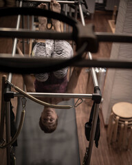 Mature woman is being prepared performing pilates exercise, training on barrel equipment. Fitness concept, special fitness equipment, healthy lifestyle, plastic.