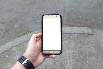 Overhead of a smartphone in a person's hand with a blank screen stopped on a street corner in a big city in order to read his cellphone