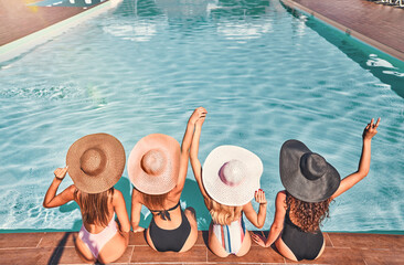 Four beautiful young woman sitting by the poolside