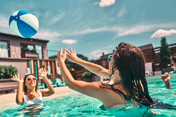 Young women plays in the pool with a beach ball