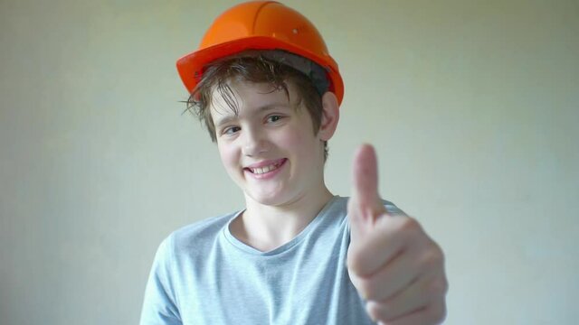 portrait of a funny cheerful boy in a construction helmet