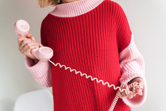 Woman holding vintage phone receiver with twisted&dagger;cable