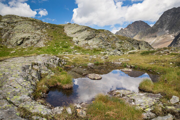 Reflection of the sky in water basin in landscape of national park Hohe Tauern, Austria.