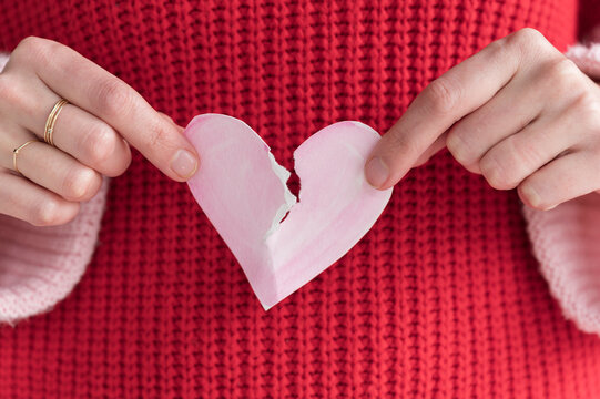 Woman ripping paper heart in half