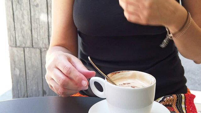 SLOW MOTION: Lifestyle woman with a surgical mask drinking a cappuccino cup in Italian cafe of Bologna city. Italian containment measures, social distancing of Coronavirus COVID-19 pandemic in Italy.