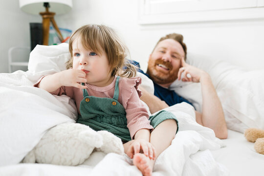 Daughter (2-3) and father watching TV†in bed