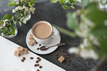 flat white coffee in a cup. brown sugar cubes and coffee beans on a table. flowers and morning sunlight. relax time. top view