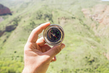 Holds the compass against the background of nature