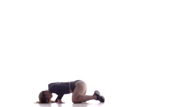 young beautiful woman dancer with long hair in fishnet tights and shorts dancing dancehall twerk, street modern dance, performs beautiful movements on the floor, long shot, isolated