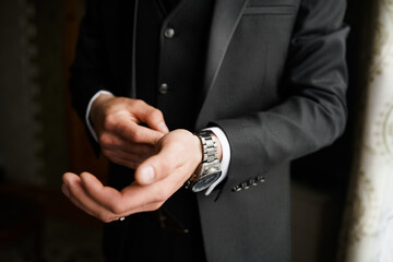 Grooms morning preparation, handsome groom getting dressed and preparing for the wedding, wearing...