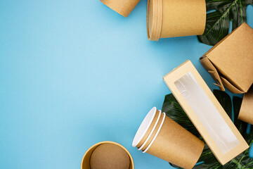 Natural eco-friendly disposable tableware, container, spoon, fork made of bagasse and bamboo fiber on a green banana leaf and blue background with a copy space. Save the earth