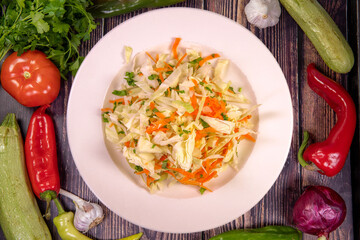 Tasty cabbage and carrot salad on a white plate, top view
