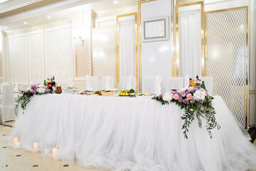 Table set for wedding reception with candles and flower bouquets. Wedding. Banquet. The chairs and round table for guests, served with cutlery, flowers and crockery and covered with a tablecloth.