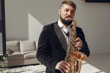 Man in a studio. Guy in a black suit. Musician with saxophone.