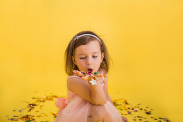 Portrait of a beautiful girl in a pink puffy dress blowing confetti from her hand . Birthday party.