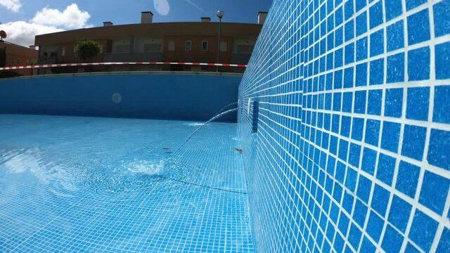 SLOW MOTION SHOT - Water jets flowing into a swimming pool with blue tiles. Return inlets in a swimming pool.