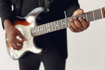 Obraz na płótnie Canvas Black man in a studio. Guy in a black suit. Musician with a guitar.