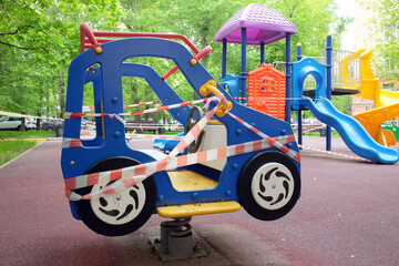 Attraction, children's car on the playground in the yard of the house is closed and wrapped in a signal tape due to coronavirus. 