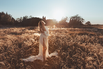 a girl in a field at sunset in a white dress