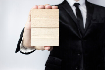 Planning, risk and business strategy, a young businessman holds in his hand four clean wooden blocks for your writing.