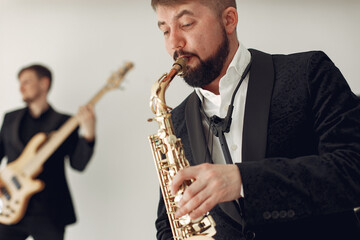 Fototapeta premium Music band in a studio. Guy in a black suit. Musician with saxophone.
