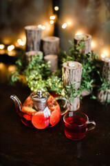 Red author's tea in a transparent teapot on the table against the background of greenery