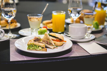 Delicious brunch type breakfast at coffee break in seminar in hotel with little sandwiches, orange juice, yoghurt, fruit, and glasses