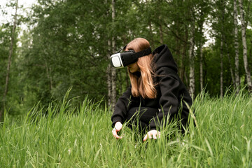 girl in virtual reality glasses touches the grass