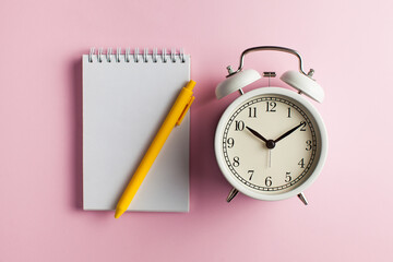 Fototapeta na wymiar Notebook, pen, alarm clock. Blank card for to-do list, timetables, text, design. Concept of time, deadline. Copy space