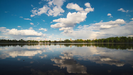 The calm idyllic landscape. The reflection of the blue sky and white clouds in a lake water