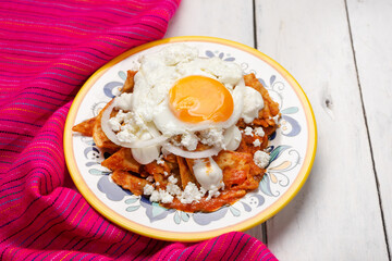 Mexican red chilaquiles with fried egg on white background