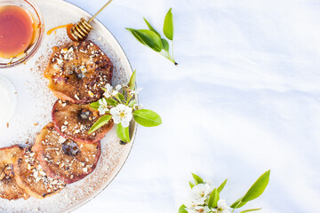  Grilled apple dessert. Roasted apple with honey and nuts on a white tablecloth. Vegan and healthy food. Copy space