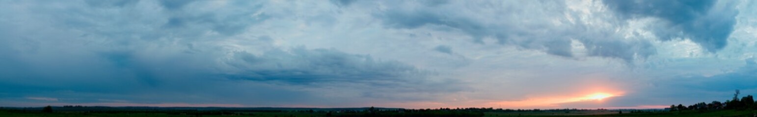 Panorama of dawn fire in the sky above the natural pasture. Golden red clouds just before sunrise. Picturesque landscape at sunrise. Beauty in nature
