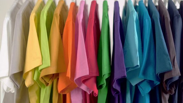  Close up of Colorful t-shirts on hangers, apparel background, Slider shot