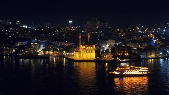 Istanbul Ortakoy Mosque and an illuminated leisure boat at night. Ortakoy district one of the most popular, lively and attractive neighborhood of Besiktas, located just by the Bosphorus Sea
