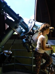 Fototapeta na wymiar A girl looks through a large telescope at the observatory