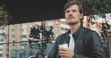 Biker drinking coffee while standing near motorcycle