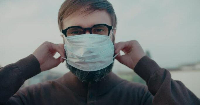 Young student man wearing protective coronavirus medical mask on city traffic street on background.Concept of health and safety life, N1H1 coronavirus, virus protection, pandemic in world