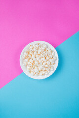 White bowl of popcorn on a blue and purple background
