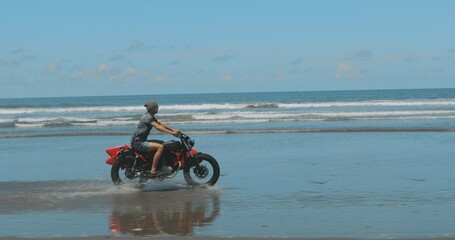 Obraz premium Motorcyclist driving his motorbike on the beach