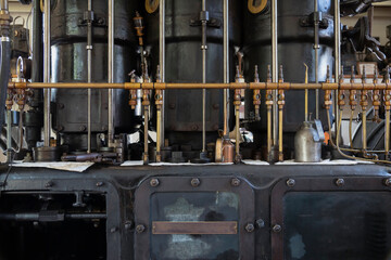 A partial view, eye level perspective, of the workings of an antique steam powered engine

