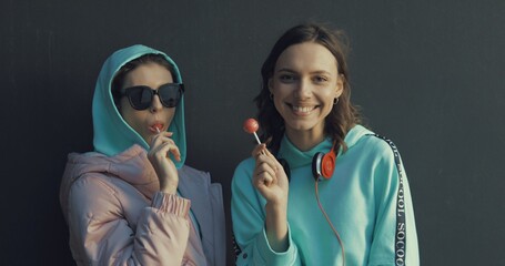 two beautiful young girls sucking lollipops