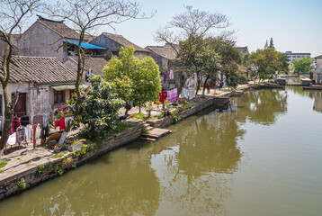 Tongli, JIangsu, China - May 3, 2010: Lines of drying colorful laundry along green water canal...