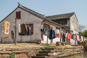 Tongli, JIangsu, China - May 3, 2010: Colorful line of laundry along greenish water canal with...