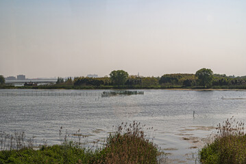 Tongli, JIangsu, China - May 3, 2010: Wide shot over gray water lake with fish pens set in green environment under light blue sky.