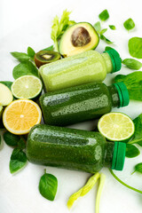 a side view of a set of several green beverage detoxes surrounded by selected fruits and vegetables.