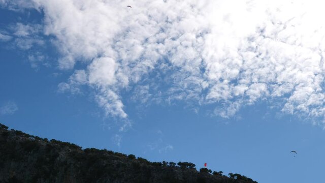 paragliders in blue sky with white clouds enjoying the sports of freedom para gliders