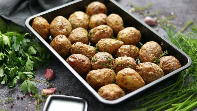 Tasty fresh homemade baked potatoes served on a metal tray. With various herbs, butter, garlic, salt