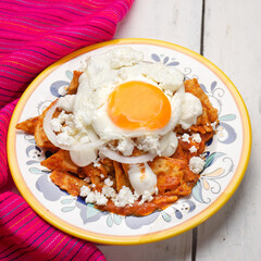 Mexican red chilaquiles with fried egg on white background
