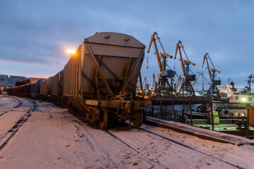 Fototapeta na wymiar General view of the cargo port. Freight railroad cars await unloading near the coal terminal. Freight gantry cranes unload railroad freight cars